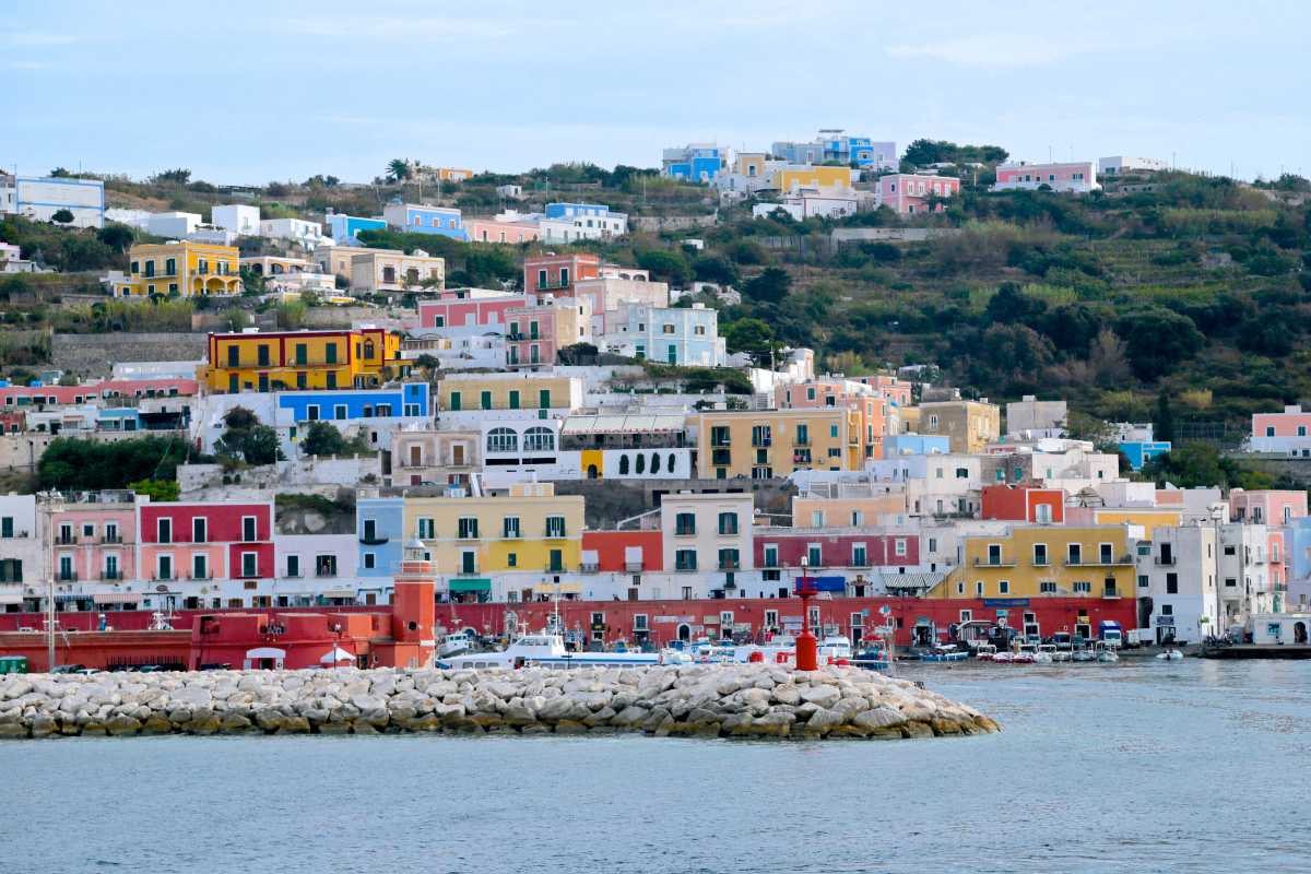 Veduta panoramica del porto di Ponza al tramonto, con traghetti e piccole barche, atmosfera estiva e accogliente