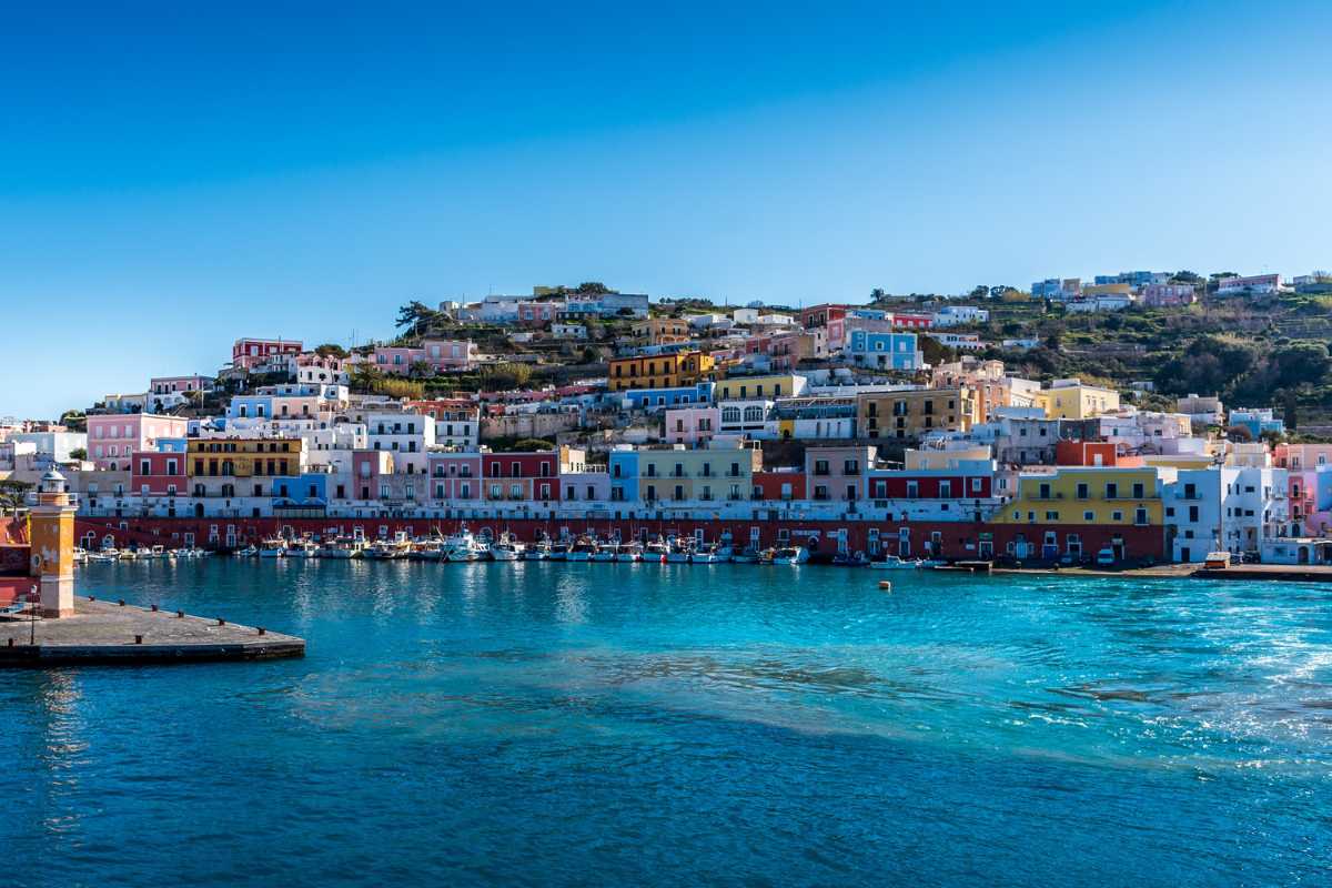 Dettaglio di una caletta di Ponza, scogli bianchi, acqua trasparente, persone che nuotano, atmosfera rilassata tipica dell’isola
